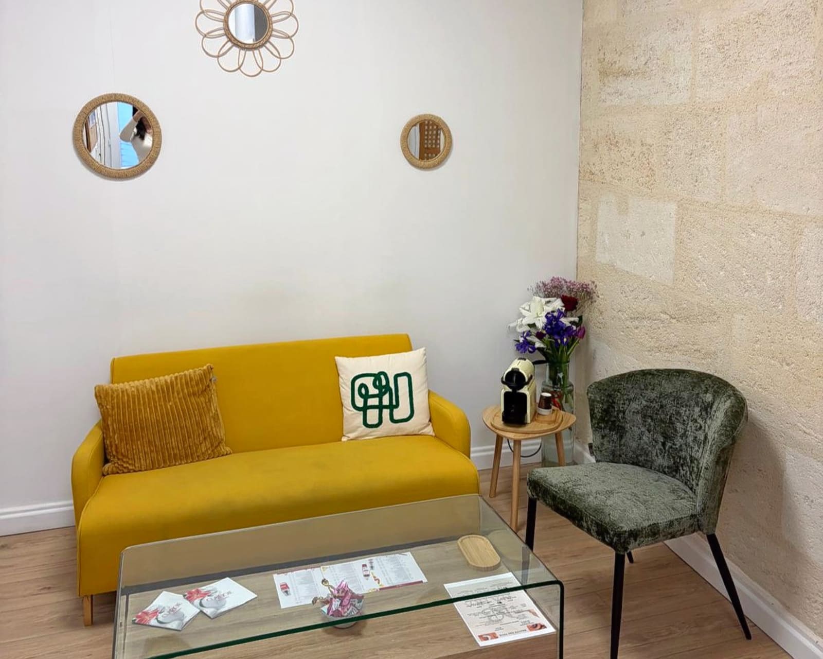 Le salon d’accueil de l’institut, canapé jaune et murs en pierre